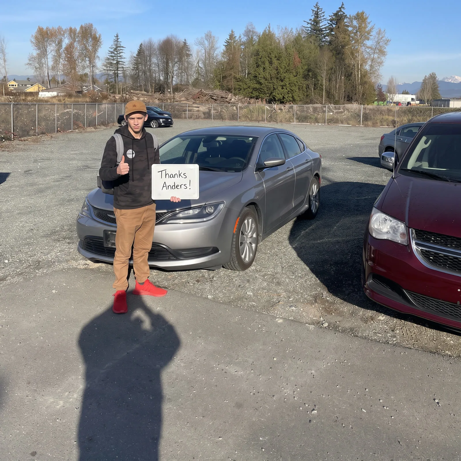 Young man giving a thumbs-up with his silver Chrysler 200