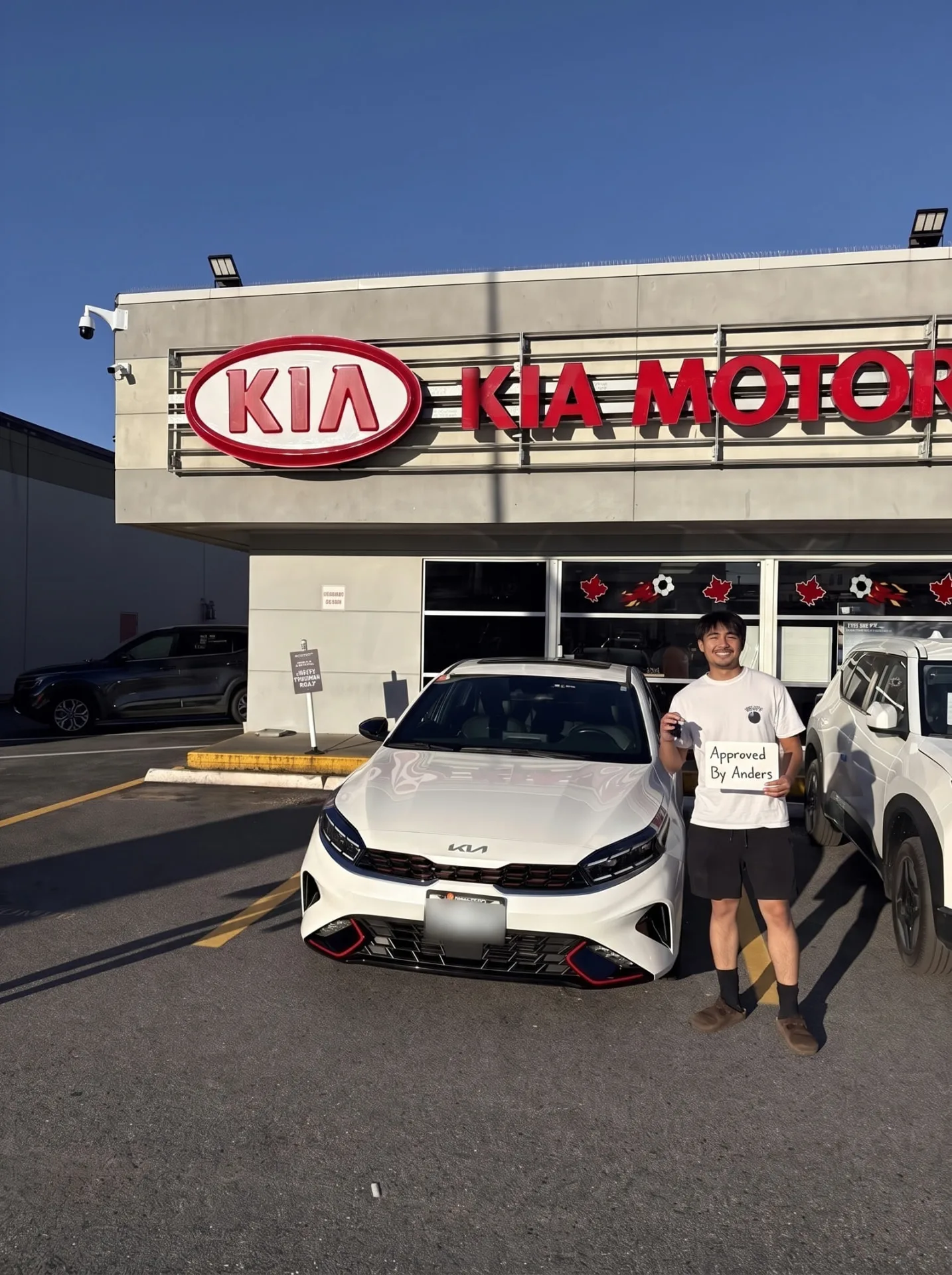 Young man with his white Kia Forte GT at the Kia store