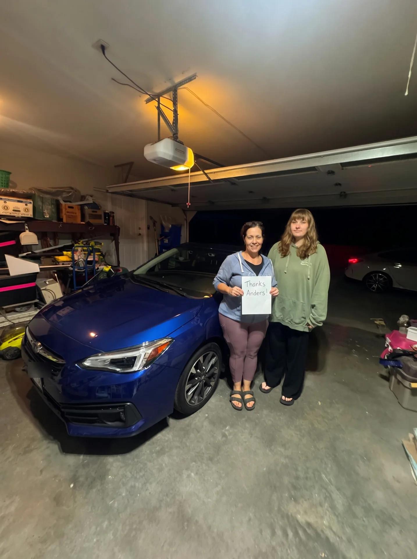 Mother and daughter with their new blue Subaru Impreza in the family garage